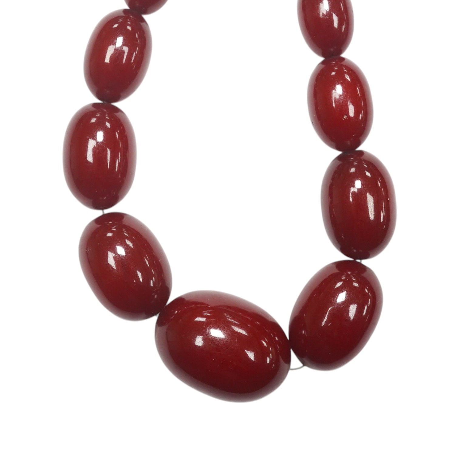 A single strand graduated oval simulated cherry amber necklace, 38cm, gross weight 47 grams. Condition - fair to good